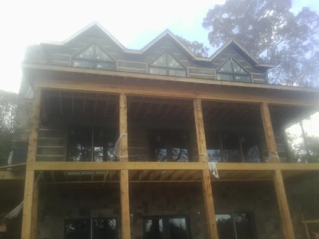 Dormers and porch framing on a large log home under construction — Roof Coating work by our crew in Howey In The Hills