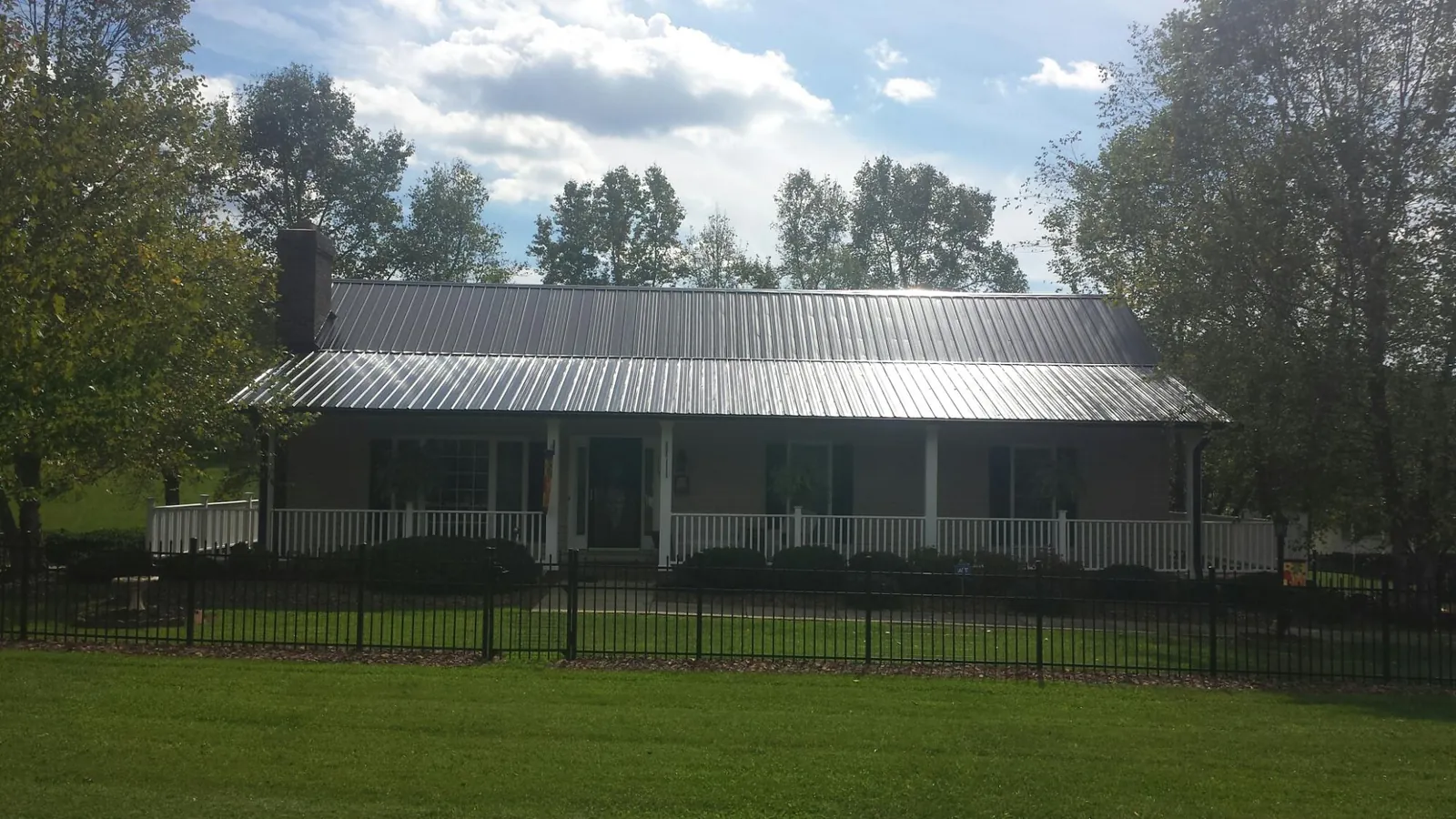Gray metal roof on a brick ranch with a full width front porch — Gutter Guard Installation work by our crew in Howey In The Hills