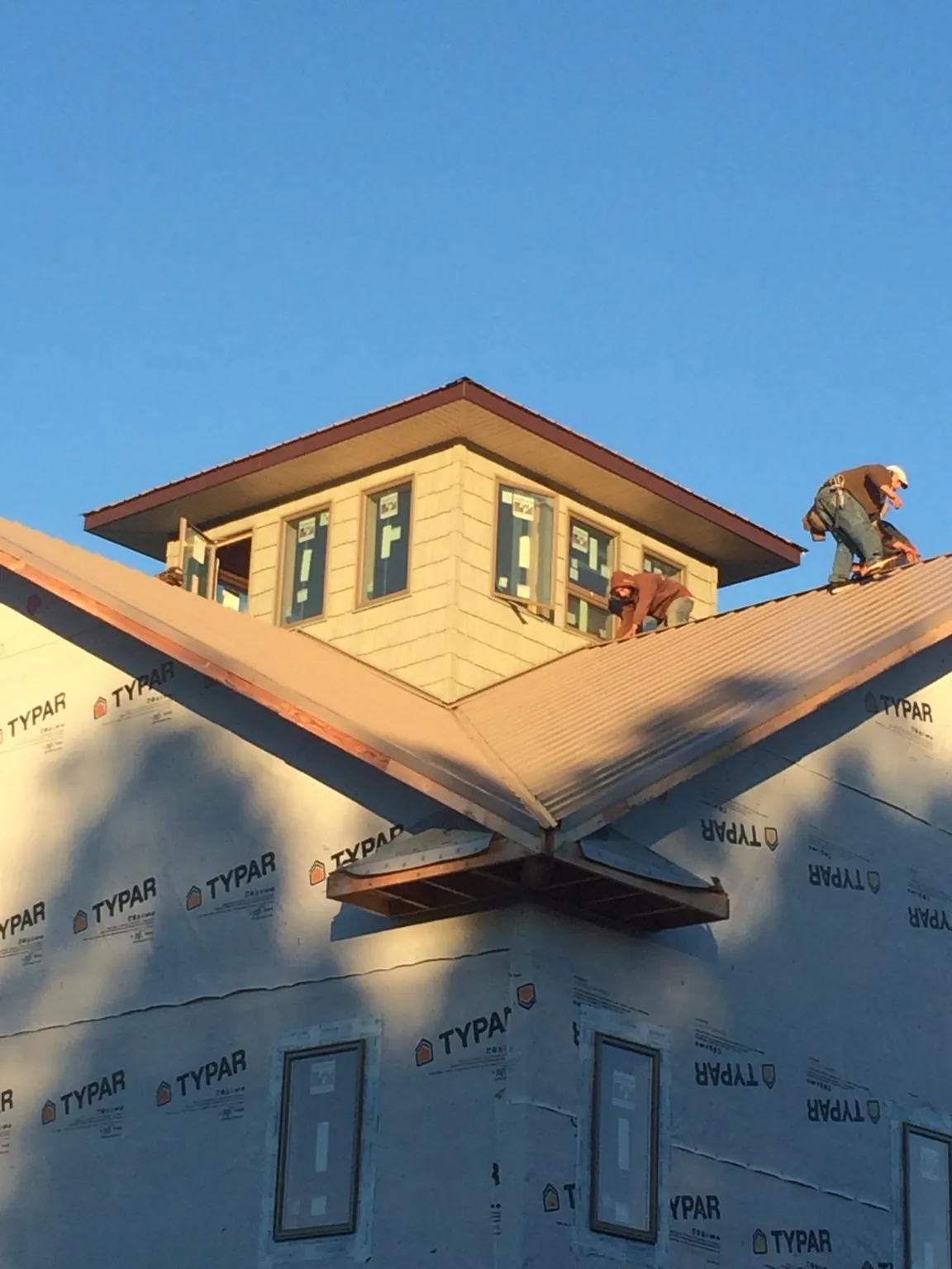 Roofers working around a rooftop cupola on a new metal roof at sunset — Roof Waterproofing in Howey In The Hills by Roofing Brothers
